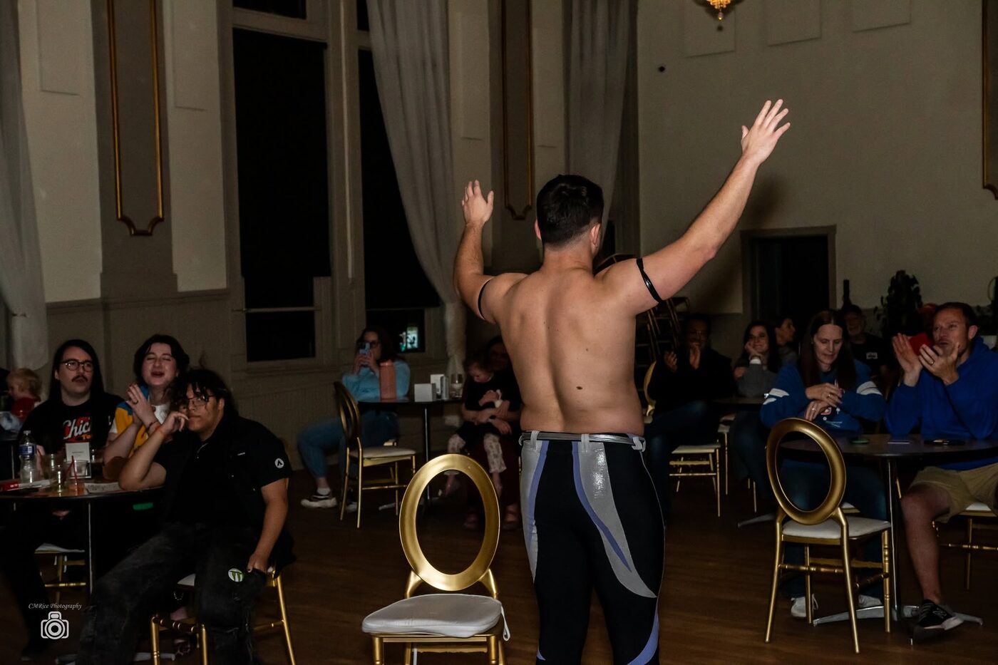 Fans clap and cheer as a wrestler raises both arms beside them at Battle at the Opera House